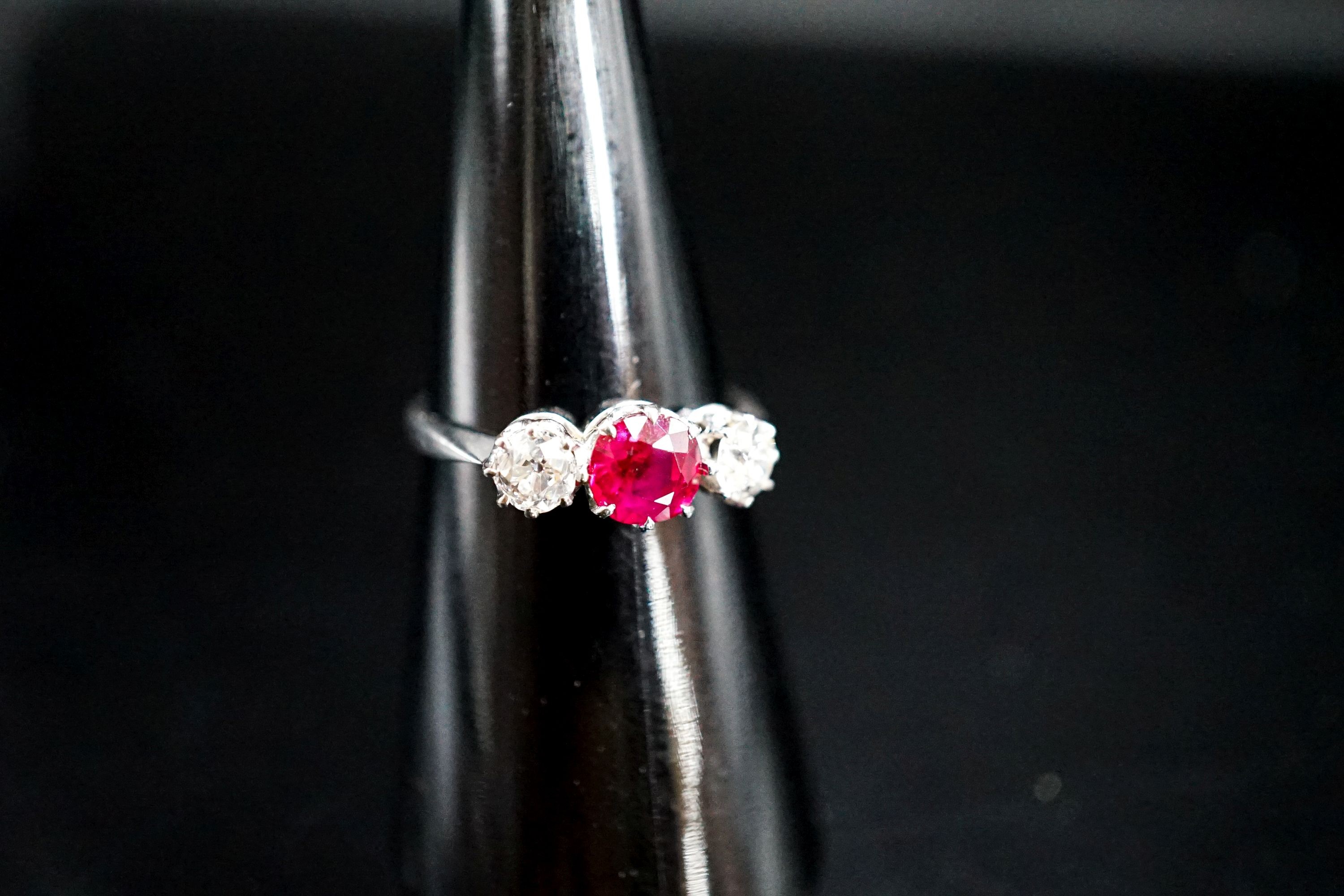 A white metal single stone ruby and two stone diamond ring, size L/M, gross weight 3 grams.